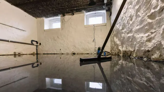 Squeegee pulling standing water across a flooded basement floor